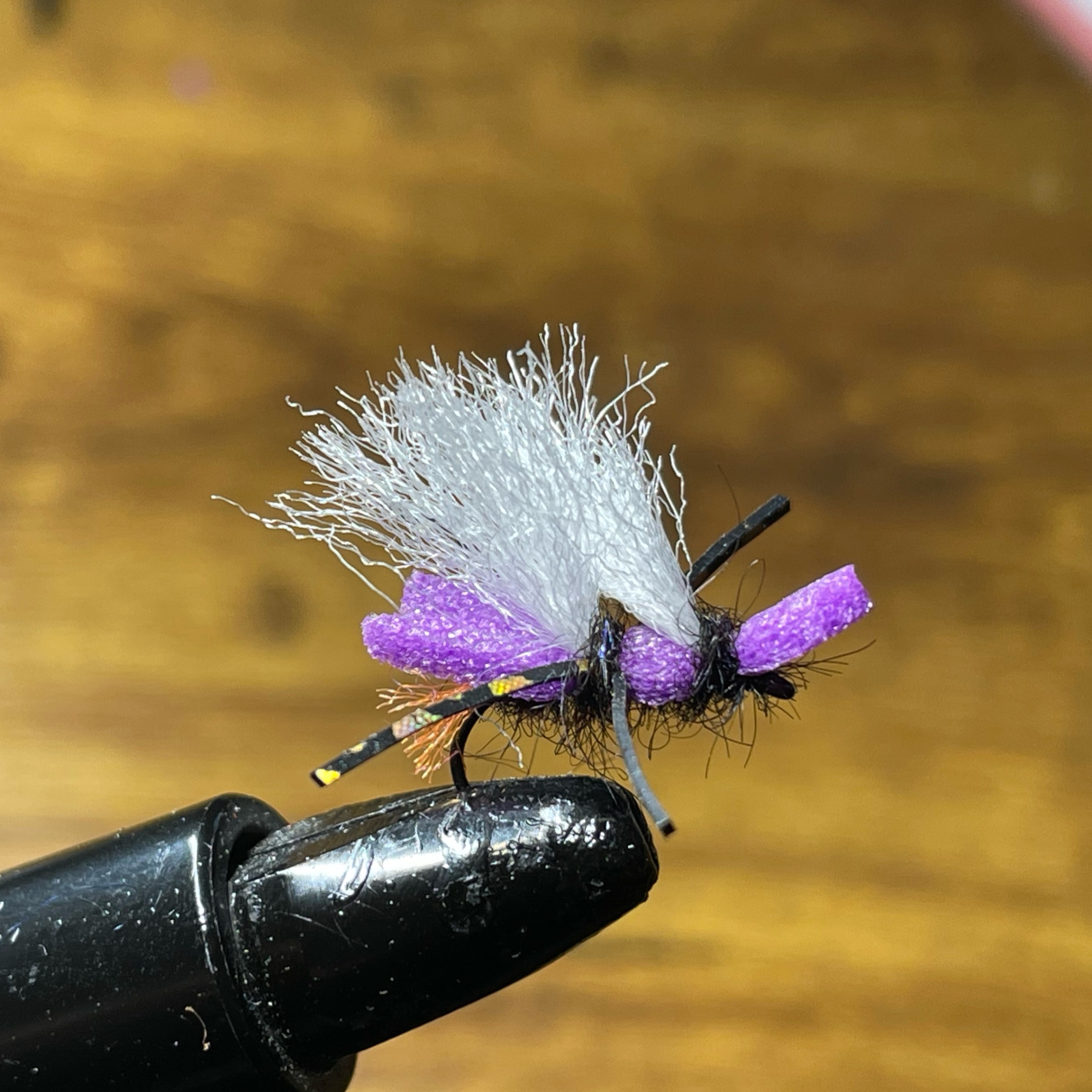 Artificial fly fishing lure with white and purple wings on hook — z is on the river
